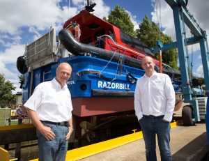 Two men standing in front of a Goodchild Marine boat.