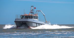 A Goodchild Marine boat navigating the vast ocean under a serene blue sky.