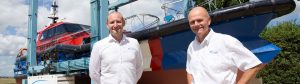 Two men standing in front of a Goodchild Marine boat.