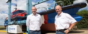 Two men standing in front of a Goodchild Marine boat.