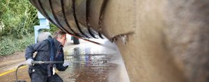 A man is using a pressure washer to clean the side of a building.