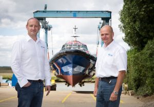 Two men standing in front of a boat manufactured by Goodchild Marine.