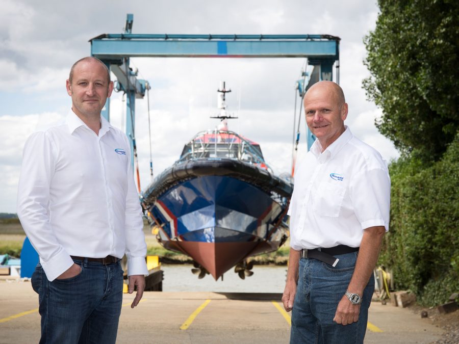 Two men standing in front of a boat manufactured by Goodchild Marine.