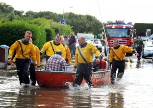A group of men from Goodchild Marine are in a boat in a flooded street.