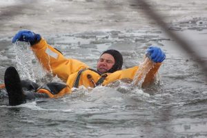 A man in a yellow jacket from Goodchild Marine is floating in the water.