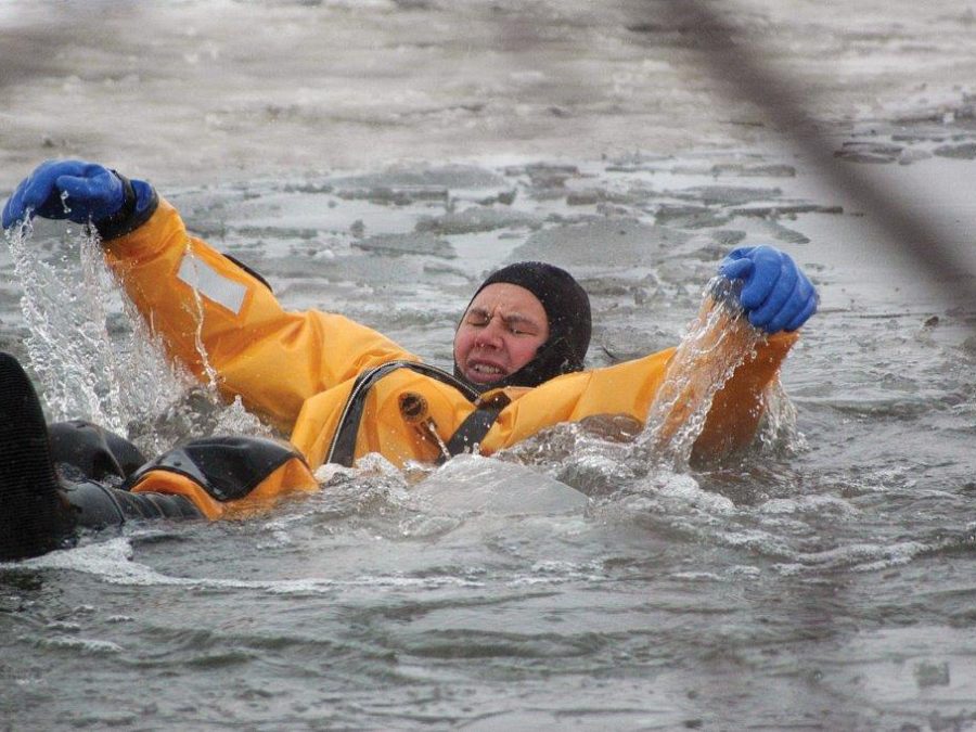 A man in a yellow jacket from Goodchild Marine is floating in the water.