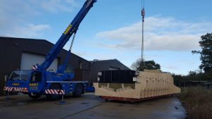 A Goodchild Marine crane effortlessly lifts a large box out of a building.